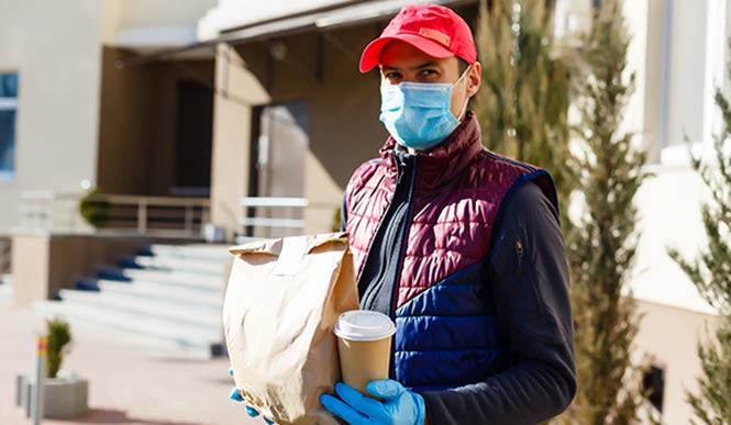 delivery driver with mask on holding food and coffee